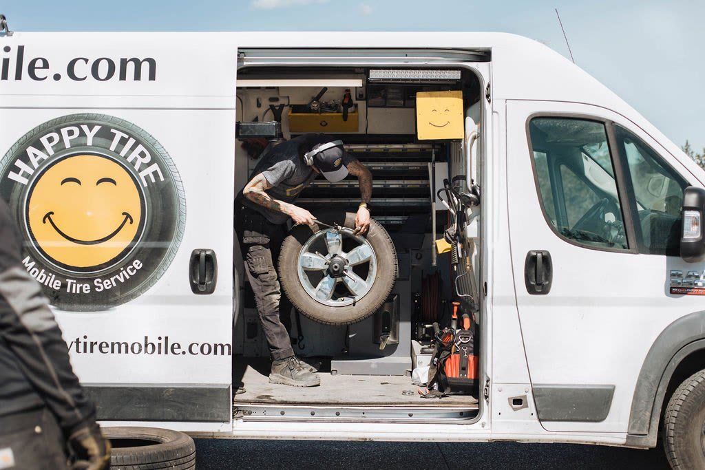 Happy Tire technician working a tire changer in the van