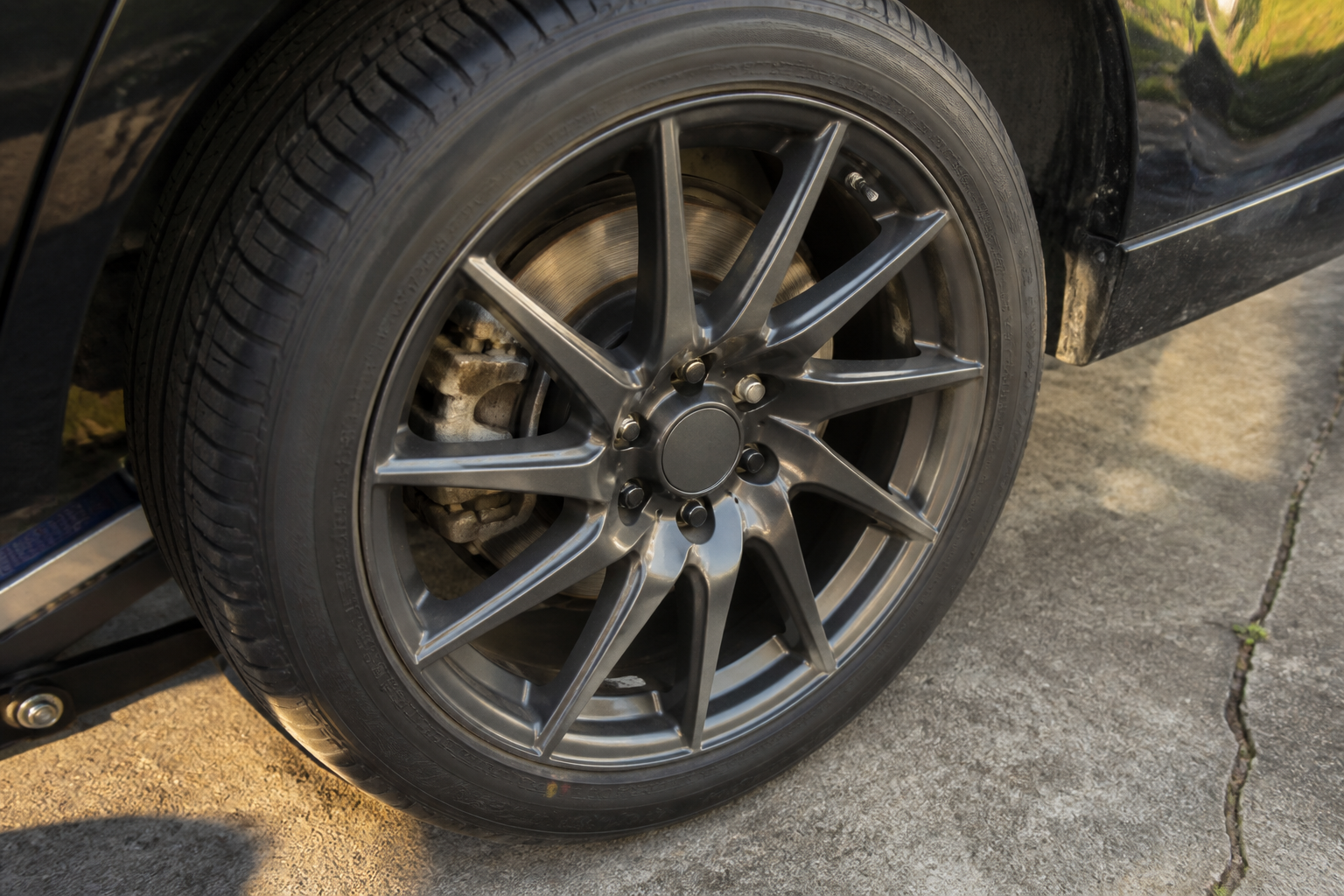 Alloy wheel on a driveway, the car raised on a jack