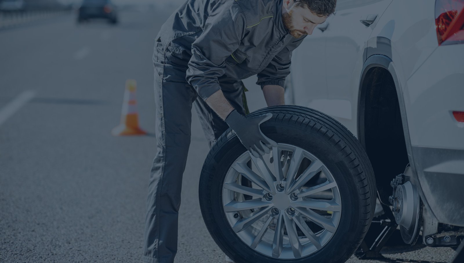 Mobile tire technician changing car tire during roadside repair